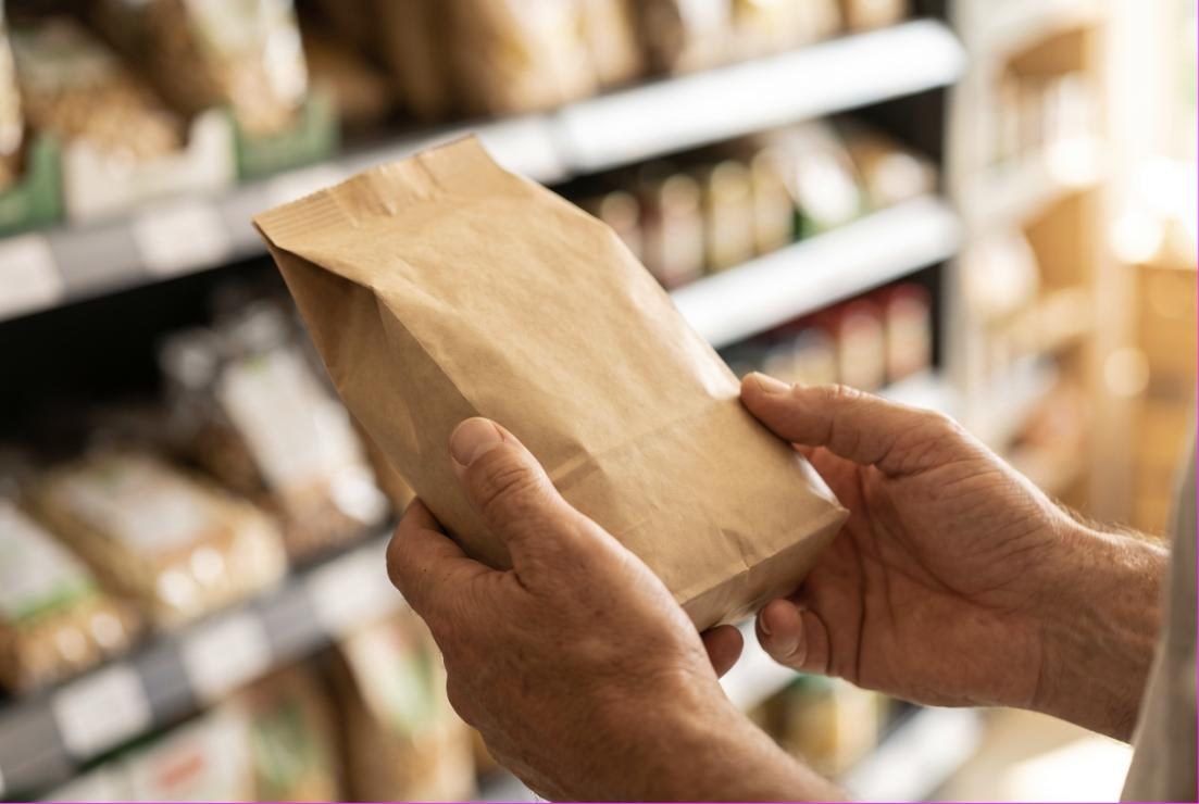 Hände drehen im Supermarkt eine Packung um und lesen die Zutatenliste