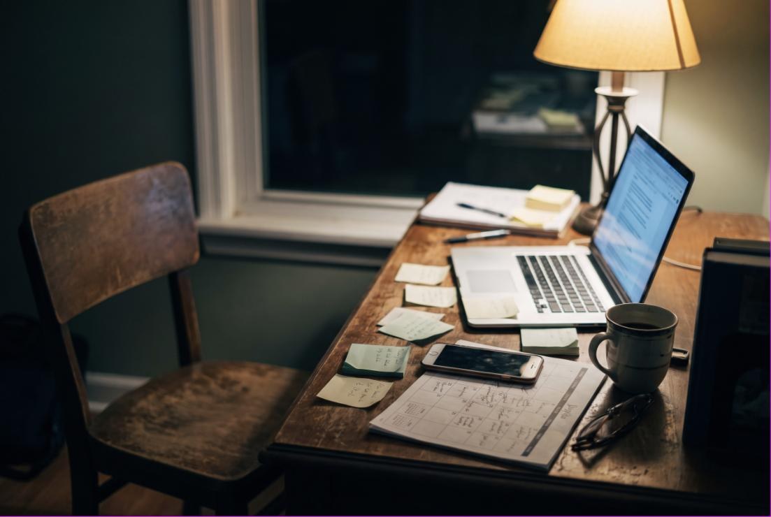 Schreibtisch am Abend mit Laptop, Notizen und Kaffeetasse